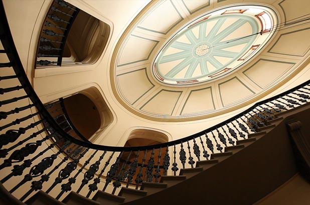 View looking up at the saloon dome which is the centre piece of EBH. The dome appears to be 3 stories above the camera. Openings looking into the saloon and a spiral staircase that follows the exterior of the saloon are visable.