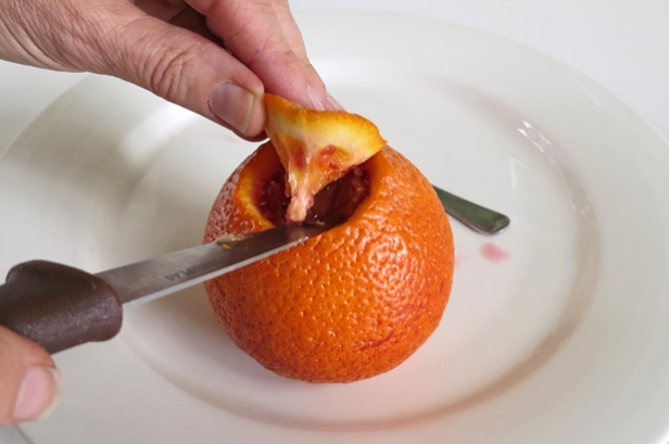 Cutting the top out of an orange.