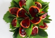 Jelly filled oranges cut into wedges and decorated with grape leaves.