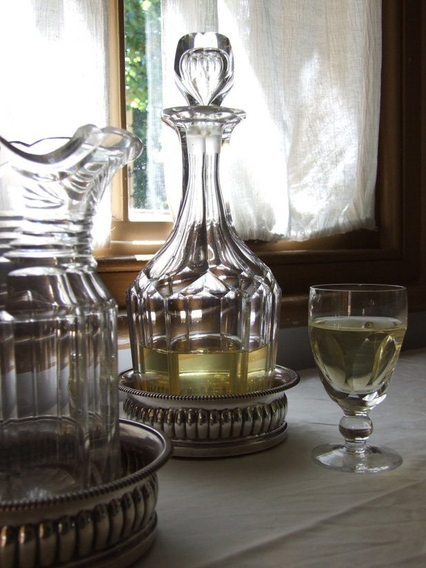 Wine decanter with glass beside a window.  