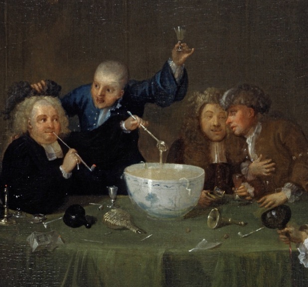 Men sitting around a punch bowl drinking.