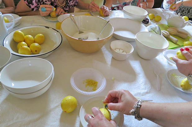 People rasping lemons with sugar cubes around a table.