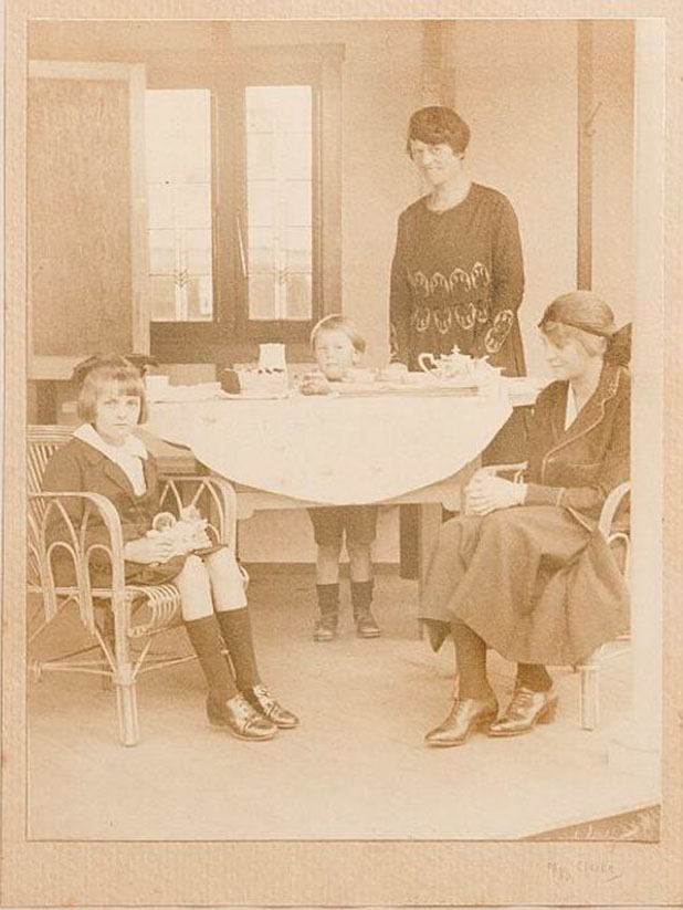 Beatrix, Walter, Mavis and Mrs David Thorburn at a table set for tea and cake, on a veranda.