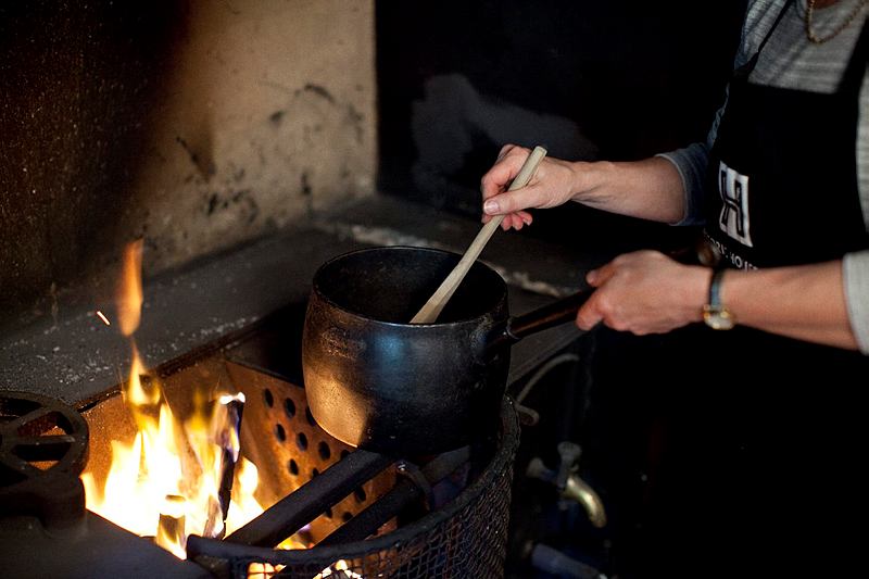 Jacqui Newling stirring a pot over the fire in the kitchen at Vaucluse House.