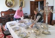 The Cook and the Curator set a table with china and silverware.