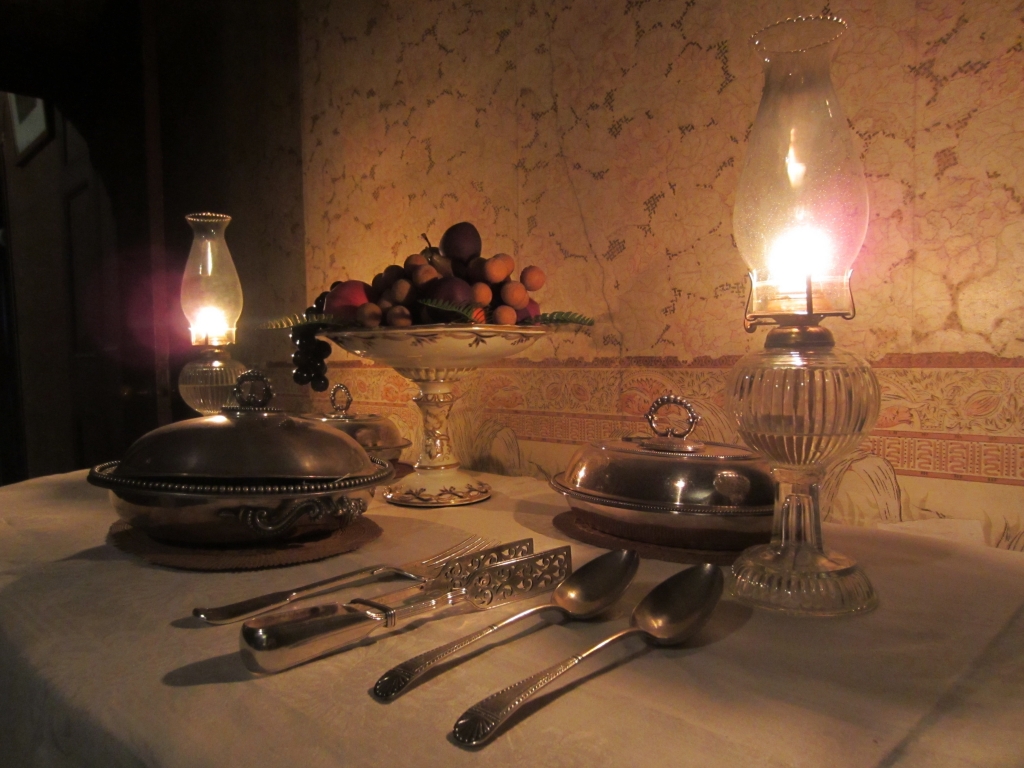 Serving table in the dining room at Rouse Hill House, lit by lamps.