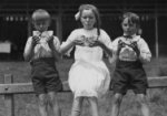 Black and white photograph of three children eating watermelon